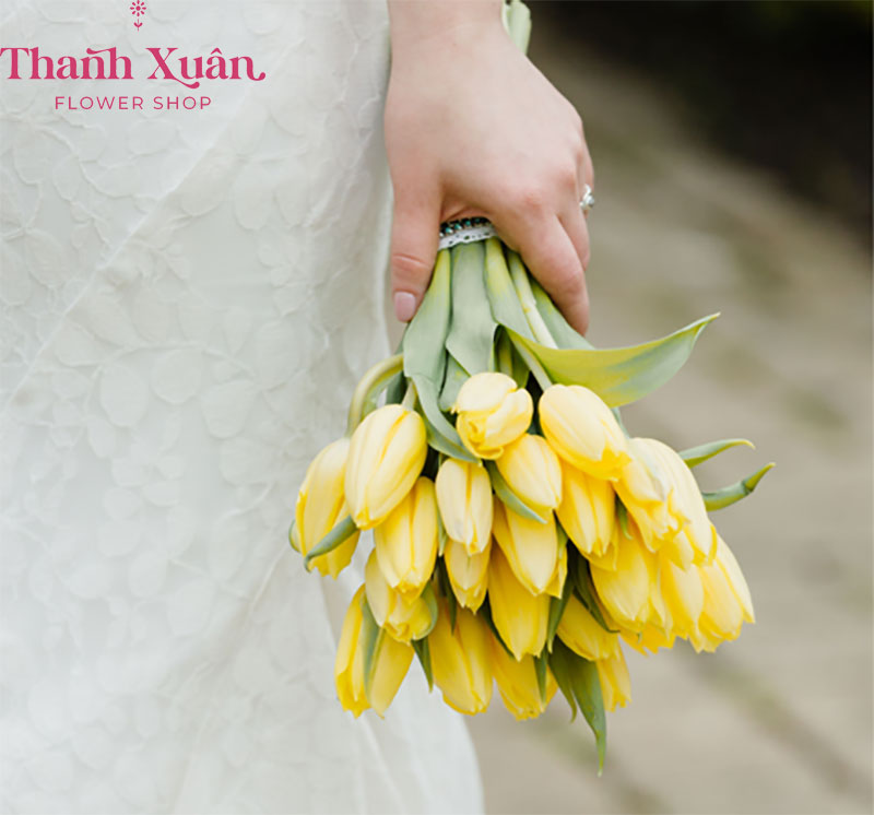Bó hoa tulip vàng tươi nổi bật giúp cô dâu trẻ trung, tươi tắn mà không mất đi vẻ sang trọng trong chiếc soiree cưới.